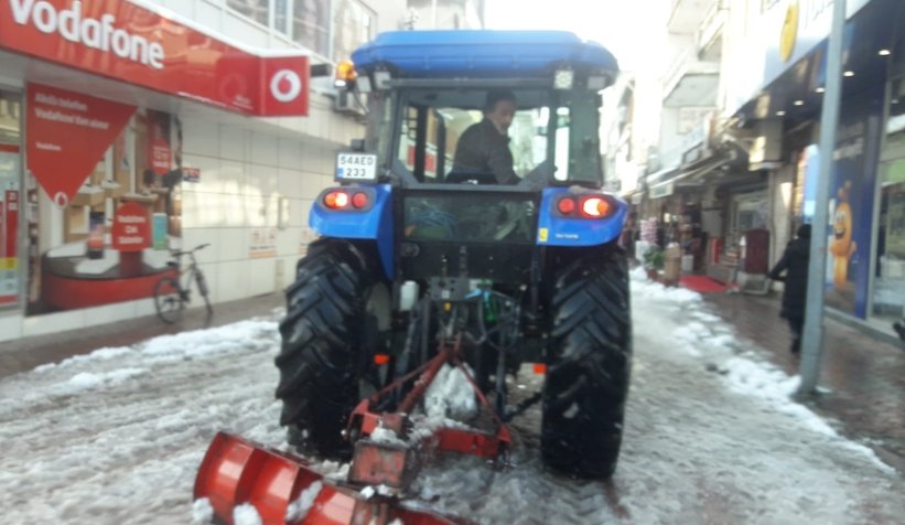 Akyazı'da muhtar ilçe merkezinde traktörle kar küredi